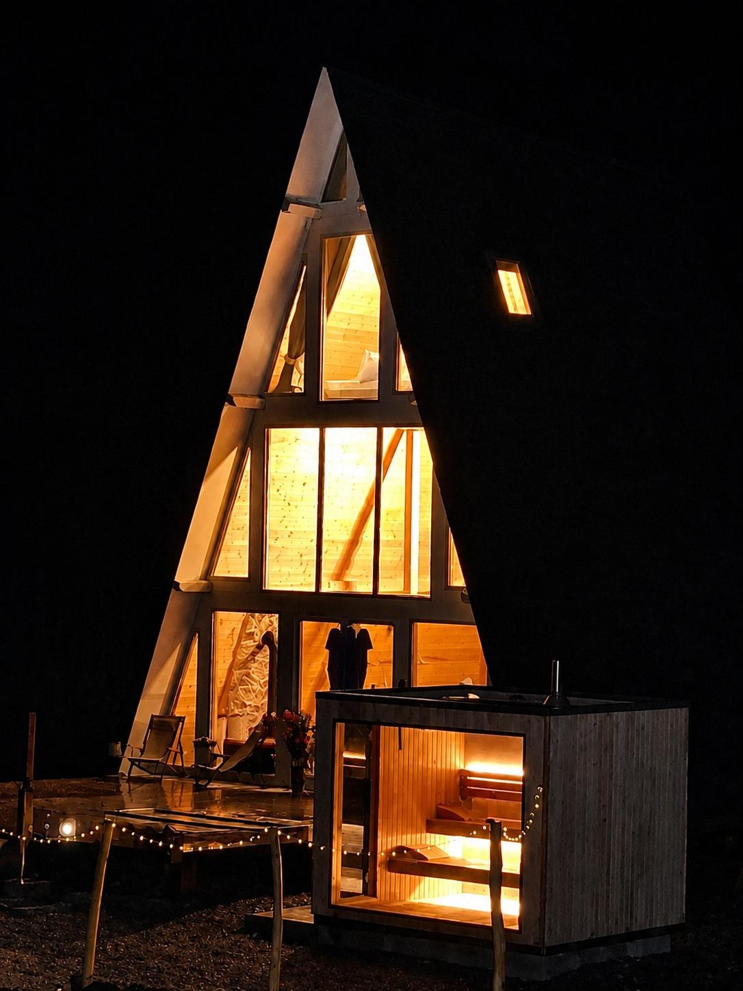 Cabana A-frame și sauna panoramică iluminate noaptea la KayLuna