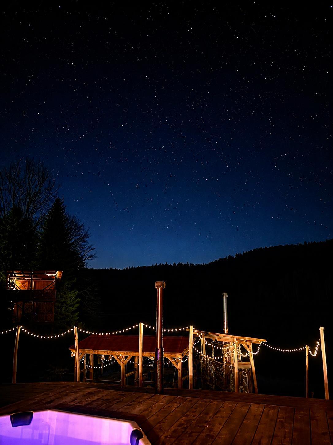 Ciubarul Cabanei KayLuna sub cer instelat, cu terasa luminata pentru seri de relaxare in Apuseni